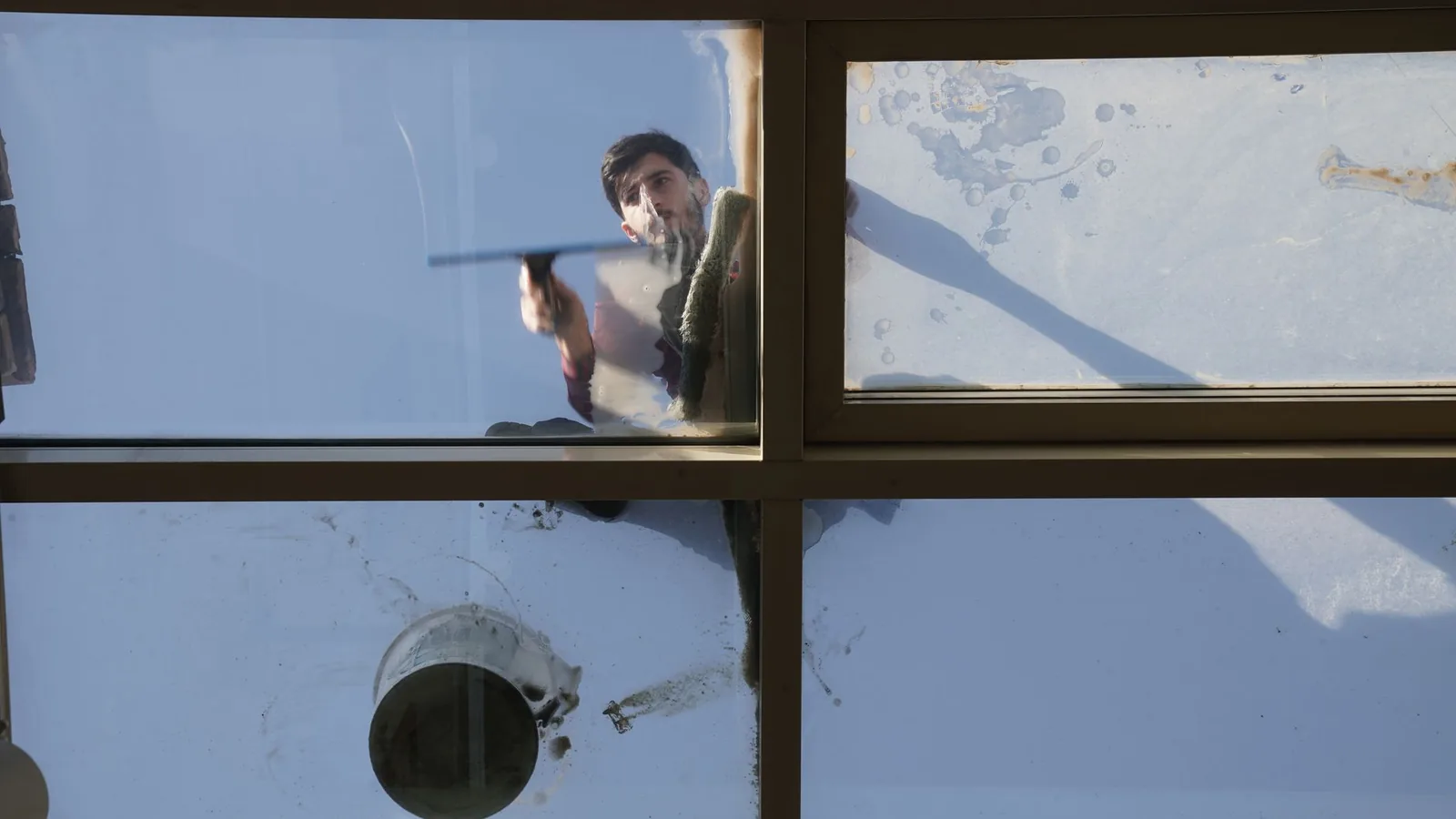 "Professional window cleaner from Dan's Window Cleaning holding a squeegee outside a home in Bloomfield, New York"
